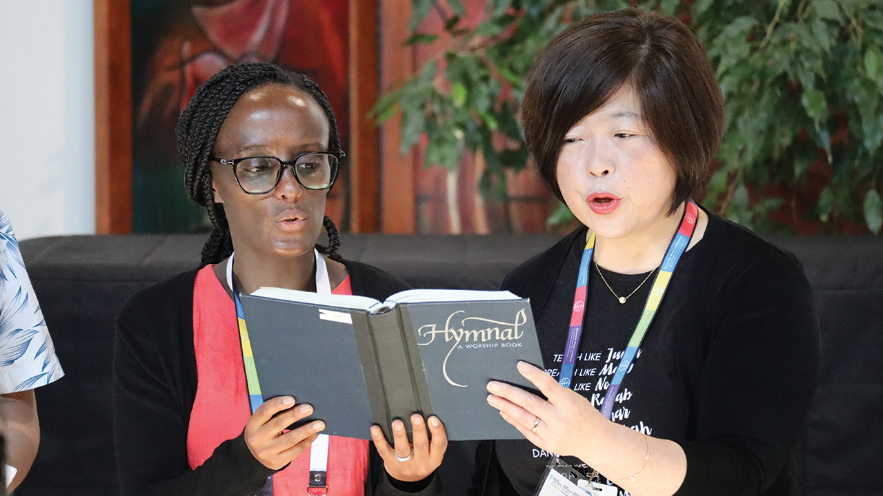 Mennonite World Conference Deacons Commission members Tigist Tesfaye, left, and Sue Park Hur participate in worship. — Henk Stenvers/MWC