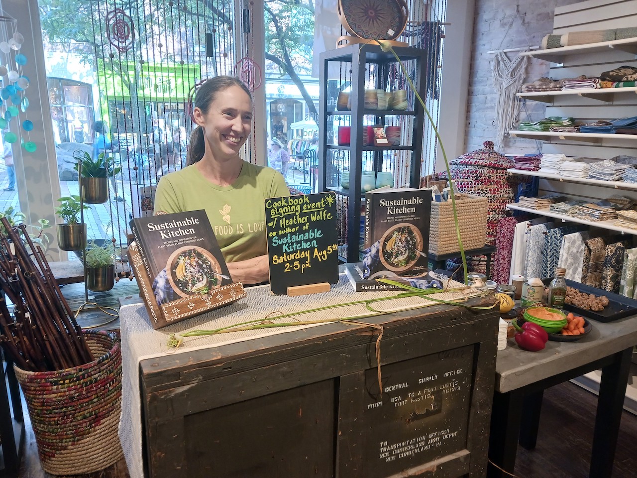 Heather Wolfe, in green shirt, sits with her book, Sustainable Kitchen.