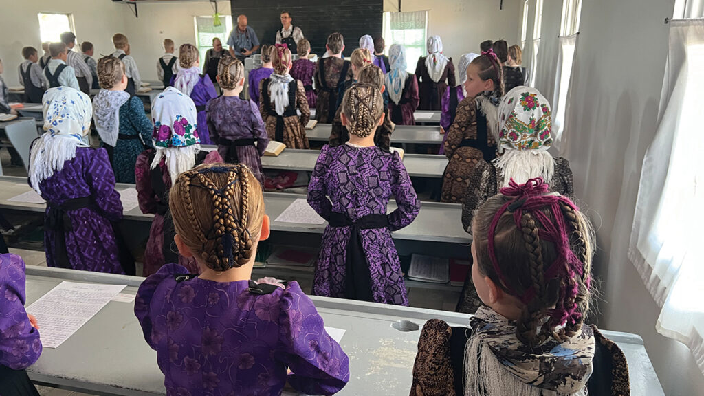 Students stand to sing hymns and recite poems and passages from the Bible. The mock school day was a highly anticipated event. One girl said her mother had braided her hair in honor of the special school day. — Patricia Funk/Die Mennonitische Post
