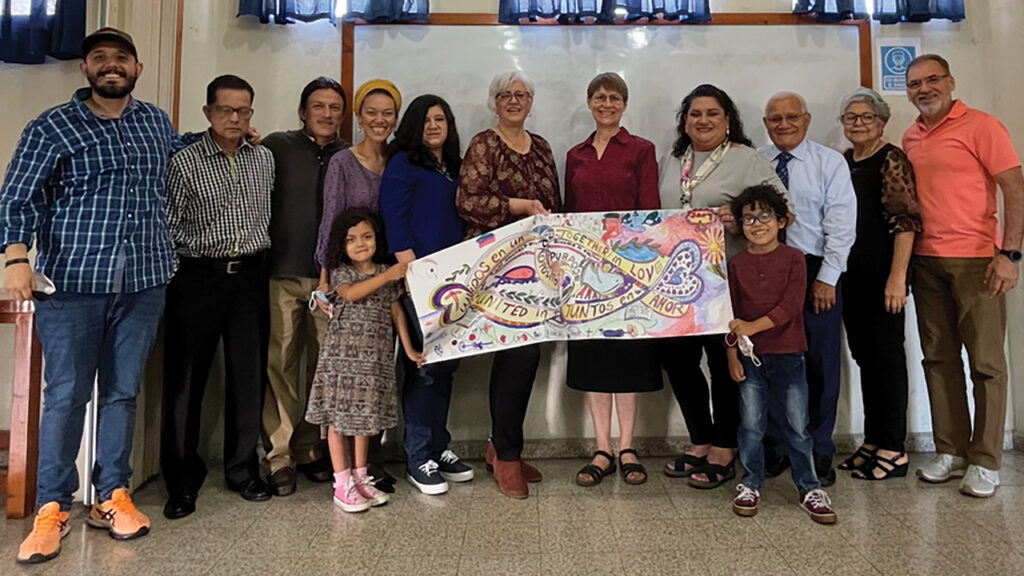 Western District Conference representatives Heidi Regier Kreider and Sandra Montes-Martinez (back row, fifth and fourth from right) present a banner to members of Iglesia Cristiana Anabautista Casa de Paz in Guatemala City in August 2022. The congregation, which has joined WDC, was started by Gilberto Flores after he retired as WDC associate conference minister. Flores and his wife, Rosa, are third and second from right. — Western District Conference