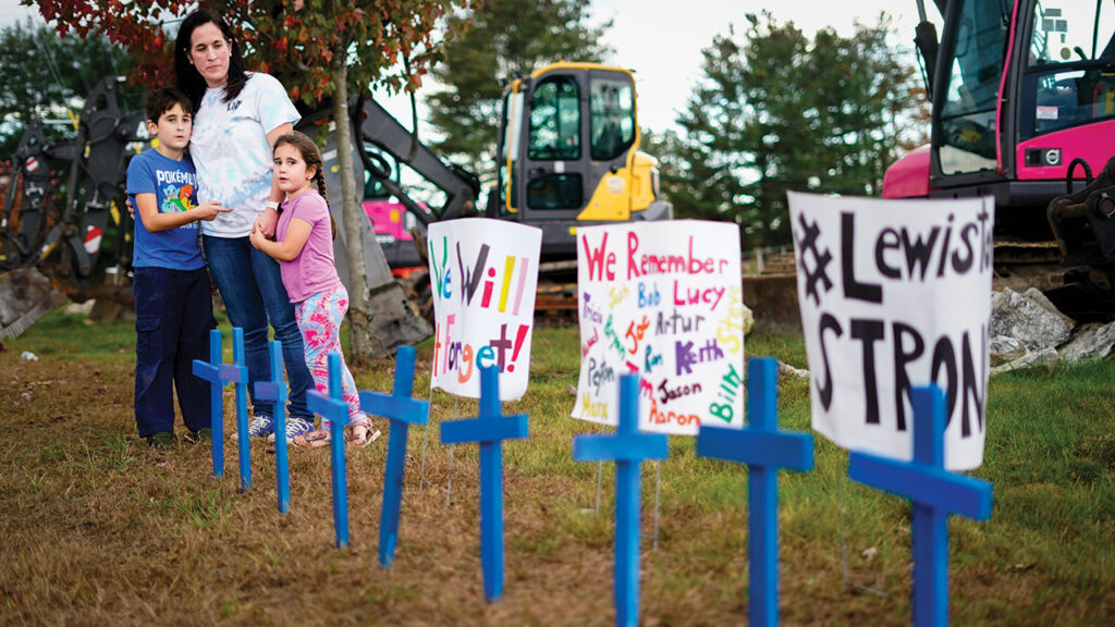 Bre Allard, accompanied by her children Zeke, 8, and Lucy, 5, pauses after planting crosses and posting signs in honor of victims of a mass shooting in Lewiston, Maine, Oct. 28. — Matt Rourke/AP
