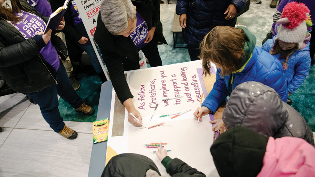 Demonstrators sign a Christmas card advocating a lasting cease-fire in the lobby of the Philadelphia building housing Sen. Bob Casey’s office. — Rachel Warriner/@rayephoto
