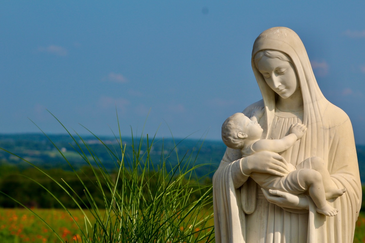 Statue of mother and child with green landscape in the background