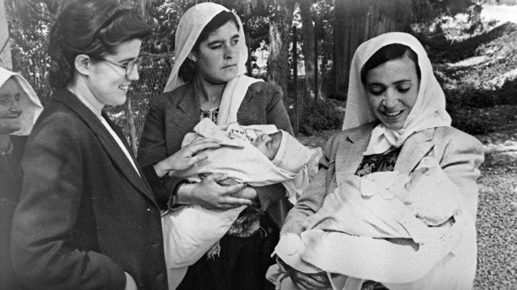Geraldine Ebersole, left, and Palestinian women in a refugee camp near Jericho in the Jordanian-controlled West Bank, who received MCC layettes for their newborns, circa 1950. — Mennonite Central Committee
