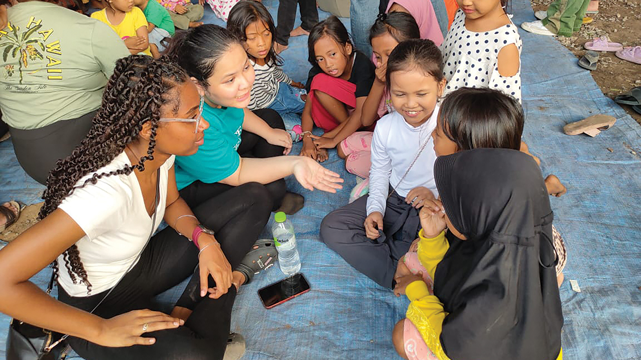 2023 Youth Venture participant Zahria Elliott, left, and Patricia, second from left, share stories with community children as part of a children’s ministry event in Jakarta, Indonesia. Patricia is a member of the youth group of GKMI ARK (Anugerah Rayon Kembangan) church in Jakarta, which joined the Youth Venture Indonesia group for daily activities. — Chialis Thuan