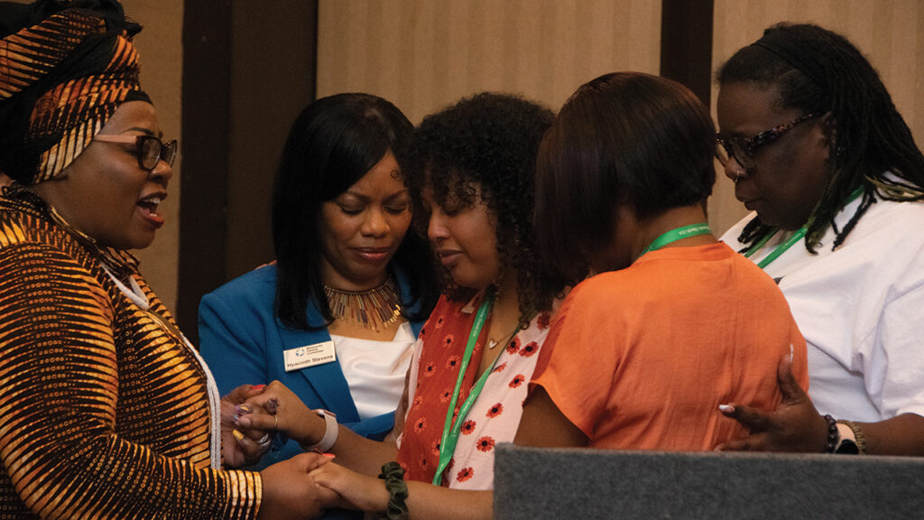 Worship speaker Abby Endashaw, center, receives blessings and prayers from Sibonokuhle Ncube, left, Hyacinth Stevens, Cyneatha Milsaps and Shana Green. — Juan Moya/AW