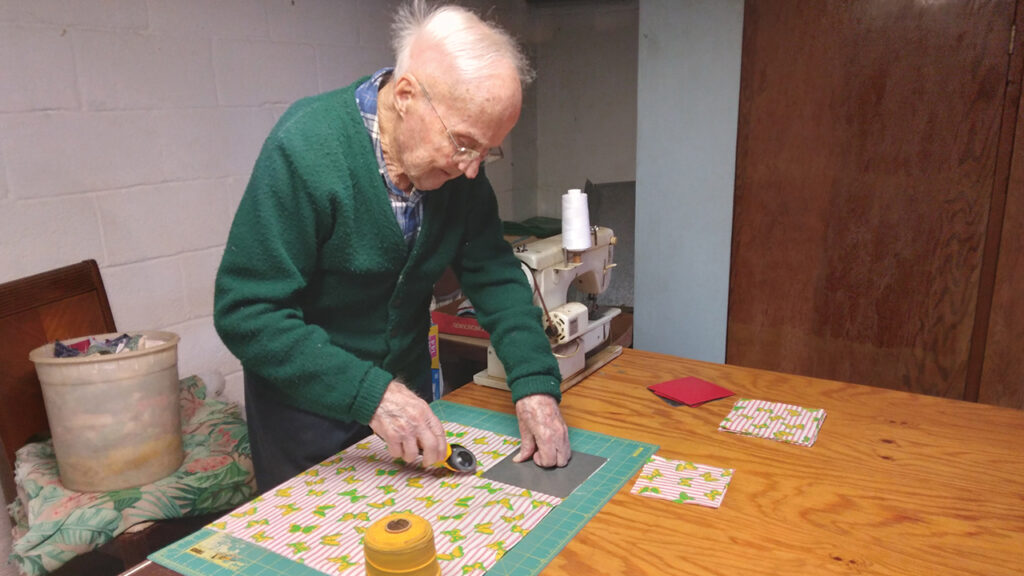 Weaver Reitz cuts fabric squares for comforters. He and his family members complete about one comforter a week. — Eileen Kinch/AW
