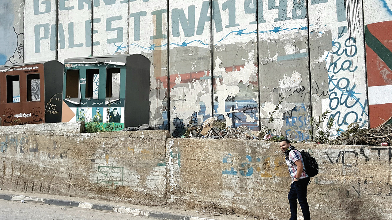 Saulo Padilla walks by the Israel separation wall in 2017 at Aida (Ayda), a Palestinian refugee camp north of Bethlehem in the West Bank, Palestine, established in 1950 by refugees from Hebron and the Jerusalem areas. — Saulo Padilla/MCC