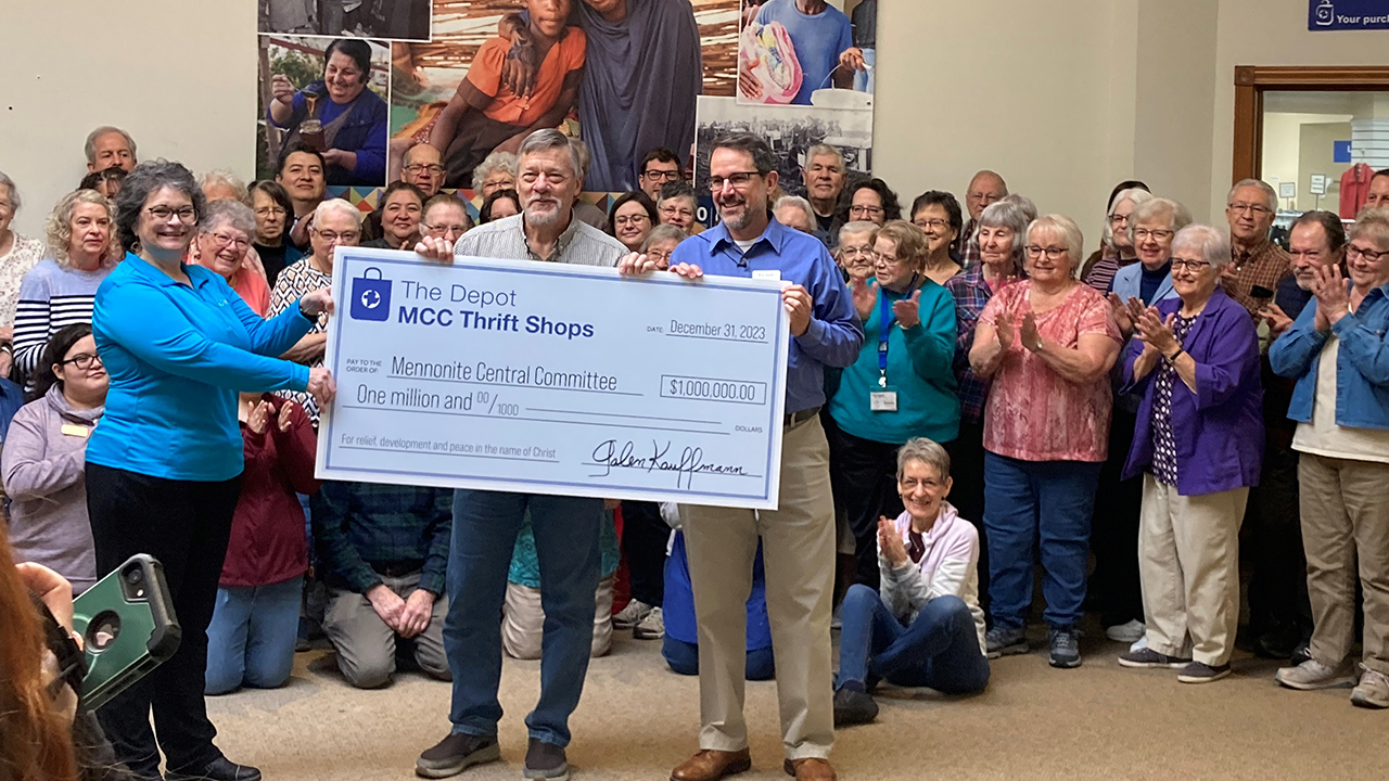 Galen Kauffmann, manager of The Depot, presents a check for $1 million to Mennonite Central Committee representatives Joy Liechty Yoder and Eric Kurtz as Depot volunteers and staff look on. — Laura Horst/MCC