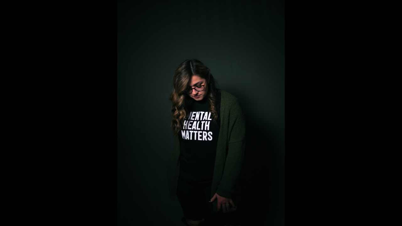 Young woman wearing black T-shirt that says "Mental Health Matters" in white letters.