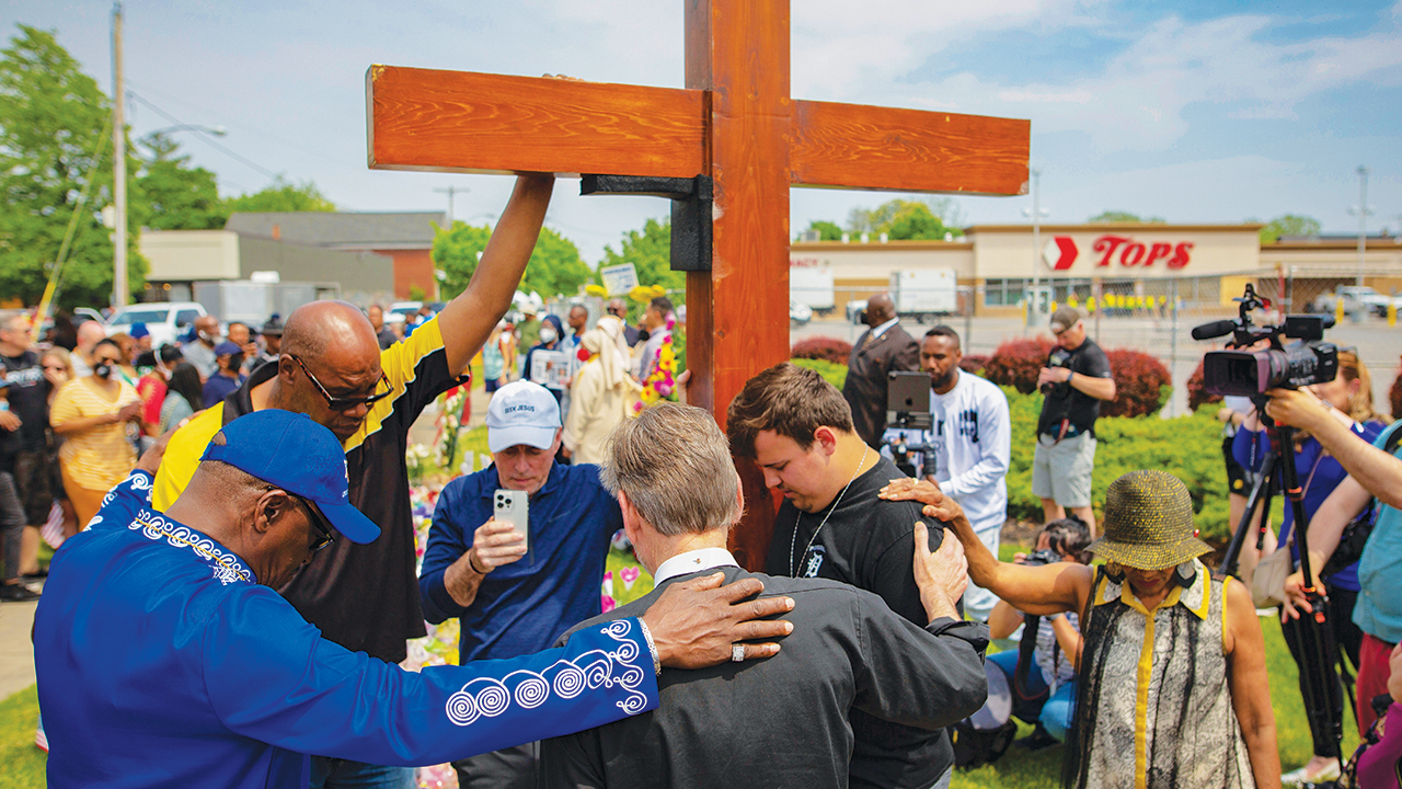 A group prays at the site of a memorial for the victims of a shooting outside the Tops Friendly Market in Buffalo, N.Y. Ten people were killed and three wounded on May 14, 2022, when a White gunman opened fire on shoppers and employees. — Joshua Bessex/Associated Press