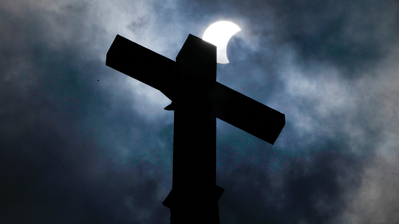 Clouds part as a partial eclipse of the sun and moon is seen atop the cross on the steeple of the New Sweden Evangelical Lutheran Church on April 8 in Manor, Texas. — Charles Rex Arbogast/Associated Press
