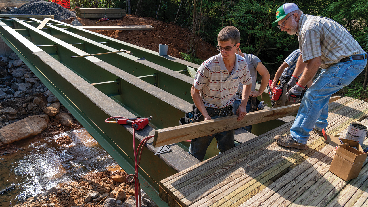 Mennonite Disaster Service volunteers Dale Shirk of Akron, Pa., and Chuck Hostetter of Hickory, N.C., install boards on a bridge in Iron Station, N.C. — Paul Hunt/MDS