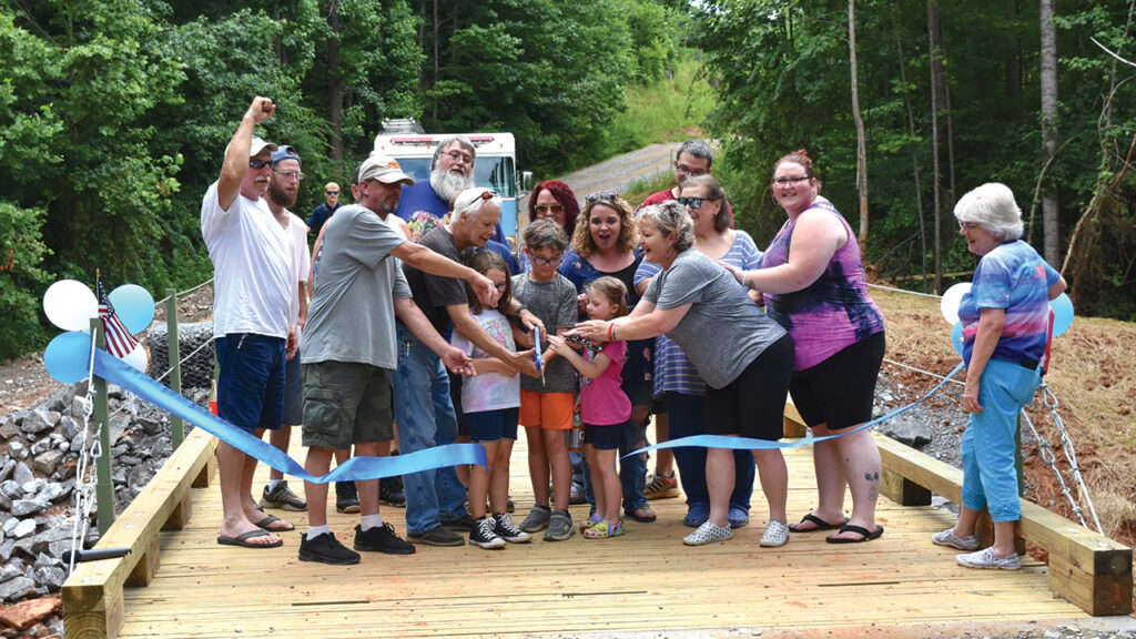 Owen Nichols and members of the Iron Station, N.C., community cut the ribbon June 29 on a bridge built by Mennonite Disaster Service volunteers. — Jesse Huxman/MDS