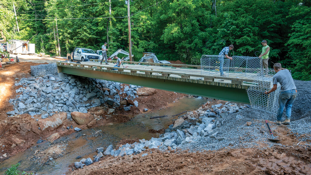 Mennonite Disaster Service volunteers put finishing touches on a bridge that helps 29 families cross a creek that washed out in January. — Paul Hunt/MDS
