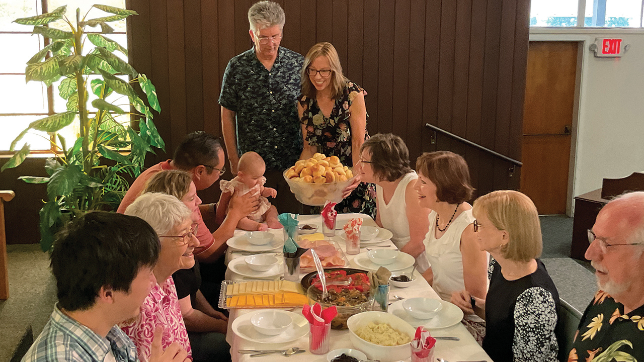 Karen and Mike McKeever, co-pastors at Mennonite Community Church in Fresno, Calif., bring zwieback to a faspa meal during fellowship time after worship on Aug. 4. — Photo by Bob Jost for AW
