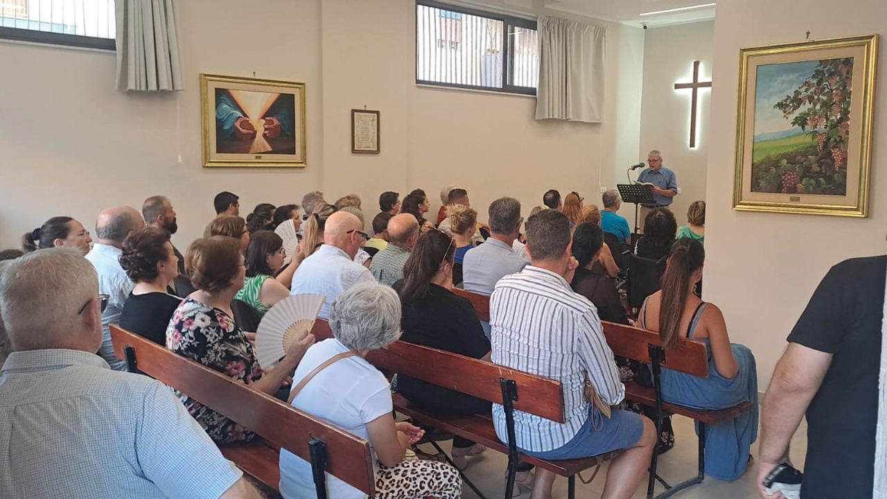 Floyd Blosser speaks during the opening service of a new congregation, Shalom Evangelical Mennonite Christian Community, in Palermo, Italy, on July 21. He and his wife, Janet, were Virginia Men­nonite Missions workers from 1981 to 1997 in Palermo. The church has also been sponsored by VMMissions. — José Arrais/MWC