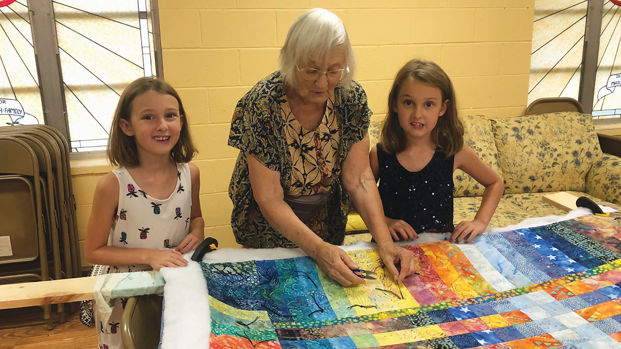Linda Yoder, center, works on a quilt with Isabelle and Gabrielle Kendall in the back of the sanctuary. — Courtesy of Wes Bergen