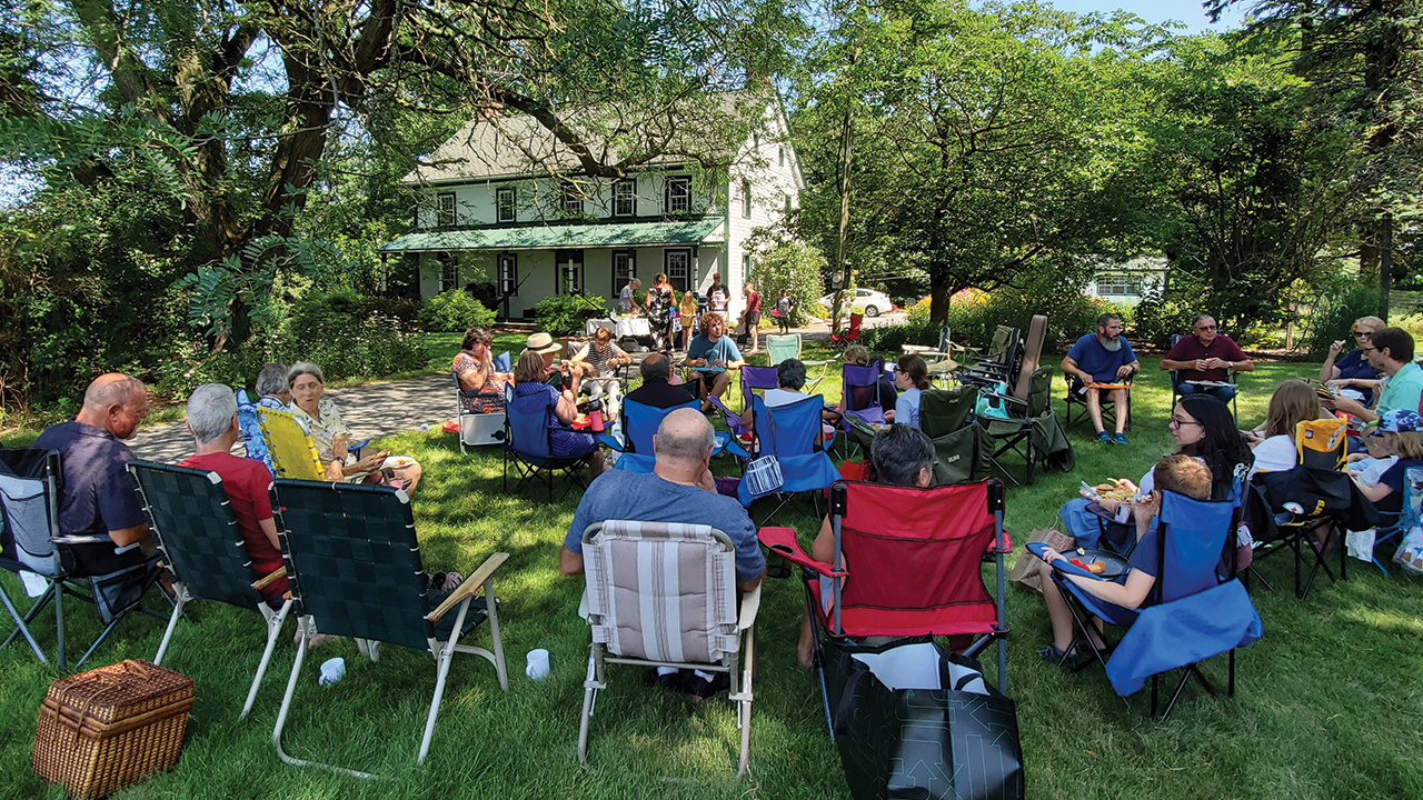 The congregation of New Holland Mennonite Church meets outdoors at the home of Wade and Jenn Esbenshade for the baptism of their son, Davin, in their stream, followed by a picnic. — Bryan Hower