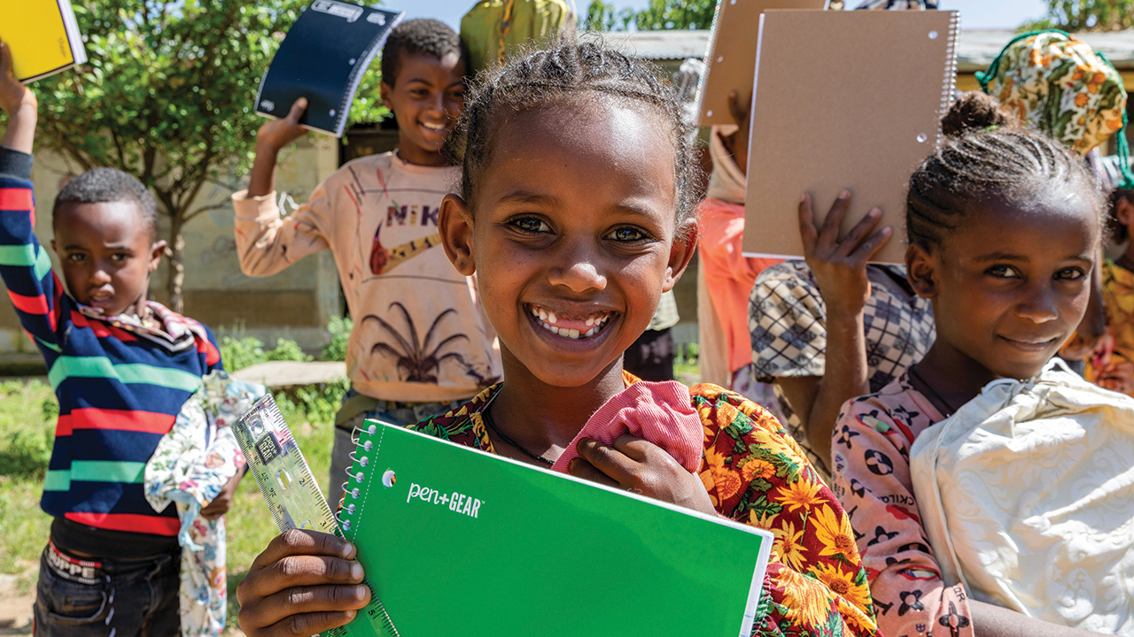 Monaliza Luel, center, and other children including Adonai Melese, left, and Melite Aregawi, right, at Daero Tekli Elementary School, hold their school supplies after receiving them in late September. — MCC/Arete
