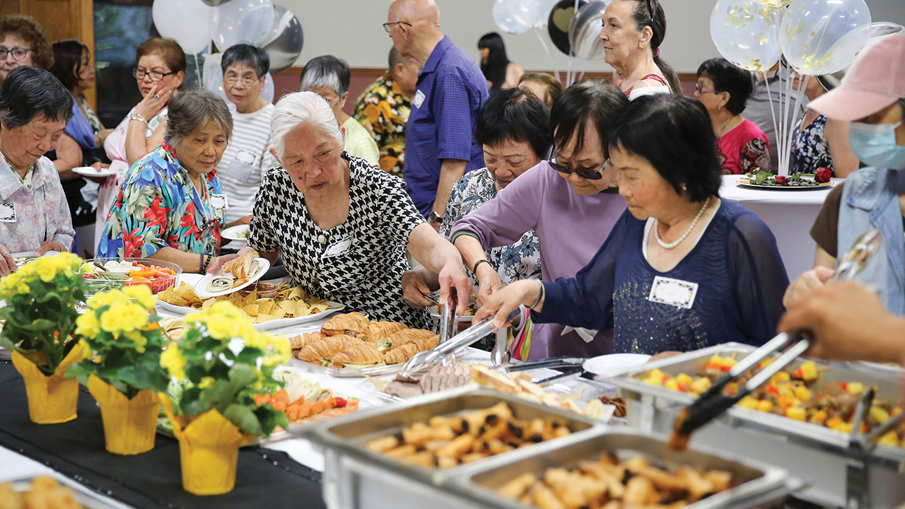 Menno Court tenants and supporters line up for food at the affordable housing organization’s 50th anniversary celebration in Vancouver, B.C. — J. Evan Kreider