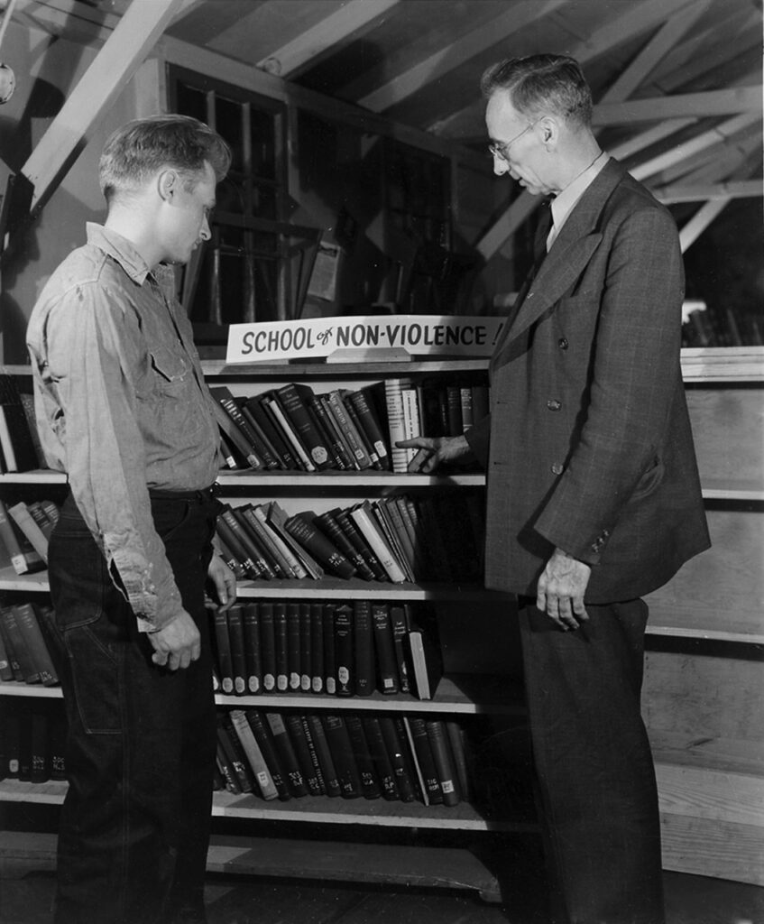 STUDENTS OF PEACE — A.J. Muste, right, a leading Protestant pacifist clergyman and frequent visitor to Civilian Public Service camps for conscientious objectors during World War II, inspects a collection of books on nonviolence at Camp No. 52 in Powellsville, Md. — Center on Conscience and War Records, Swarthmore College Peace Collection