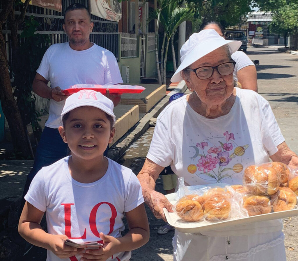 GESTURE OF PEACE — Luz Stella Garzón carries bread in her neighborhood with Isabella Barón, left, and Diego Barón in September. Comunidad Cristiana Menonita de Girardot in Colombia practices a Peace Sunday tradition called Pan y Paz (bread and peace). After the service, members walk through the neighborhood with bread and cold water to share with anyone on the street. “People welcomed us with joy, and we were able to share with them the message of peace and hope from our Lord Jesus Christ,” said Pastor Juan Carlos Moreno. — Mennonite World Conference
