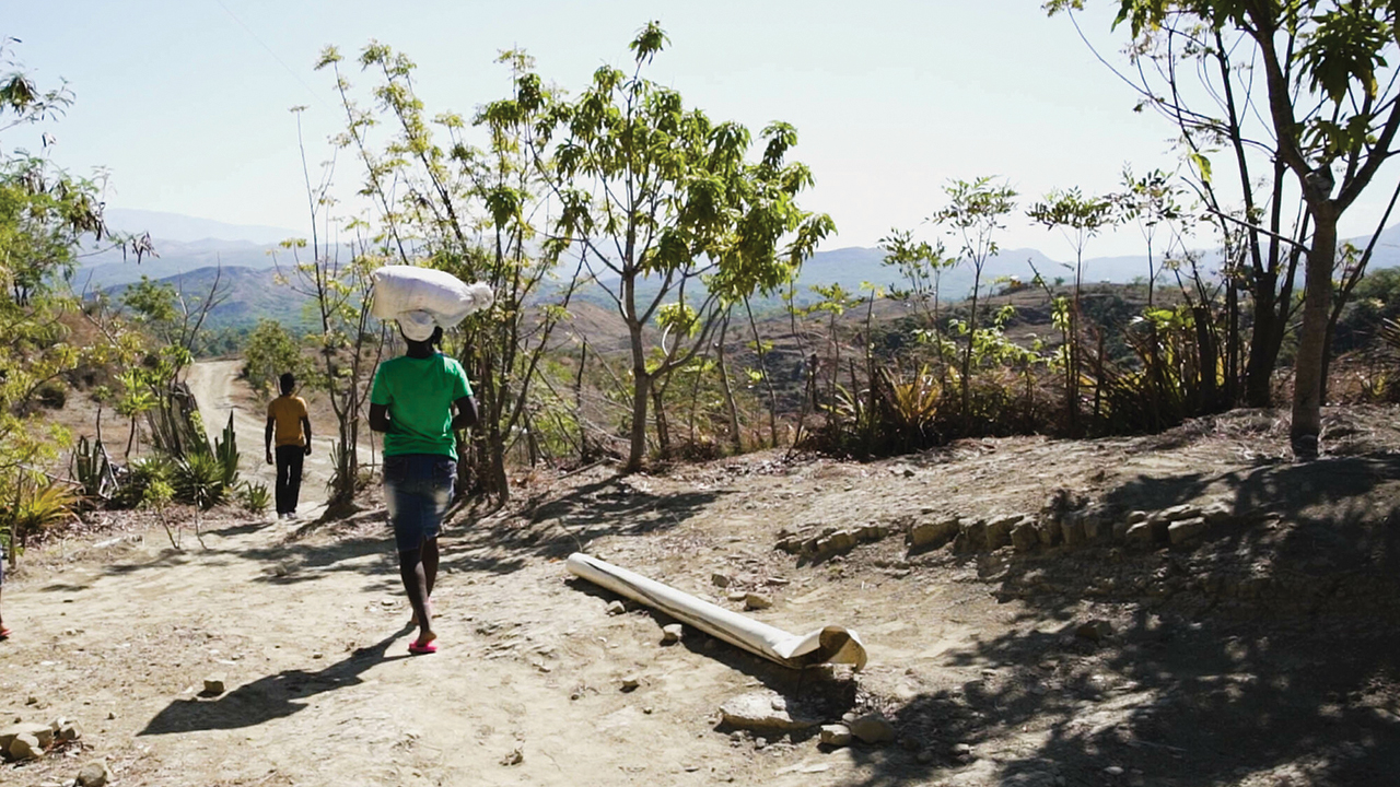 A woman heads back to her garden after receiving seed in the Artibonite mountains in Haiti. MCC’s partners support farmers who struggle with climate change and live with the risk of gang violence. — Christy Kauffman/MCC