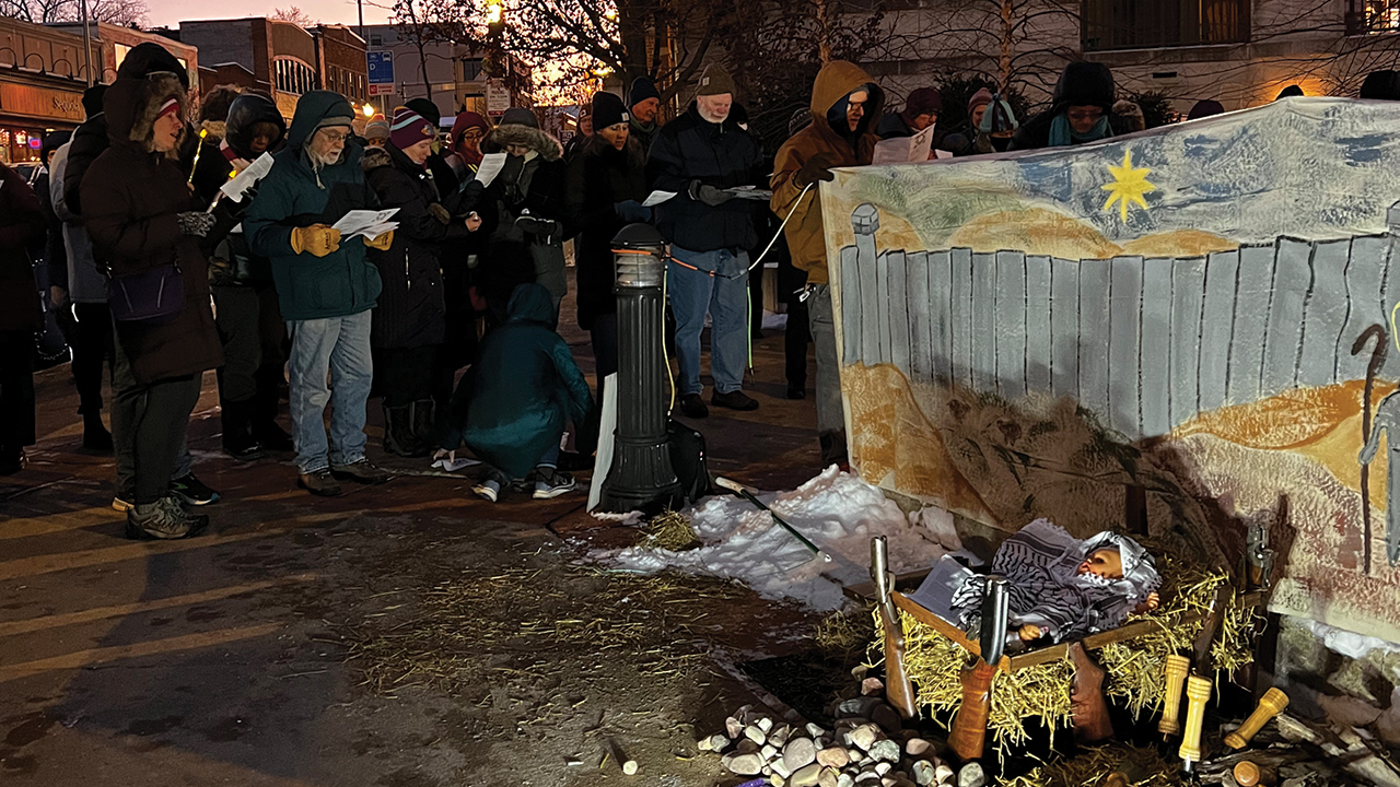 A Mennonite Action "Longest Night" vigil for a cease-fire in Gaza takes place Dec. 21 in Madison, Wis. The baby Jesus lays in a manager made from gun stocks and is swaddled with a black-and-white keffiyeh, the Middle Eastern-style scarf that has become a symbol of Palestinians’ resistance to Israeli aggression. — Mennonite Action