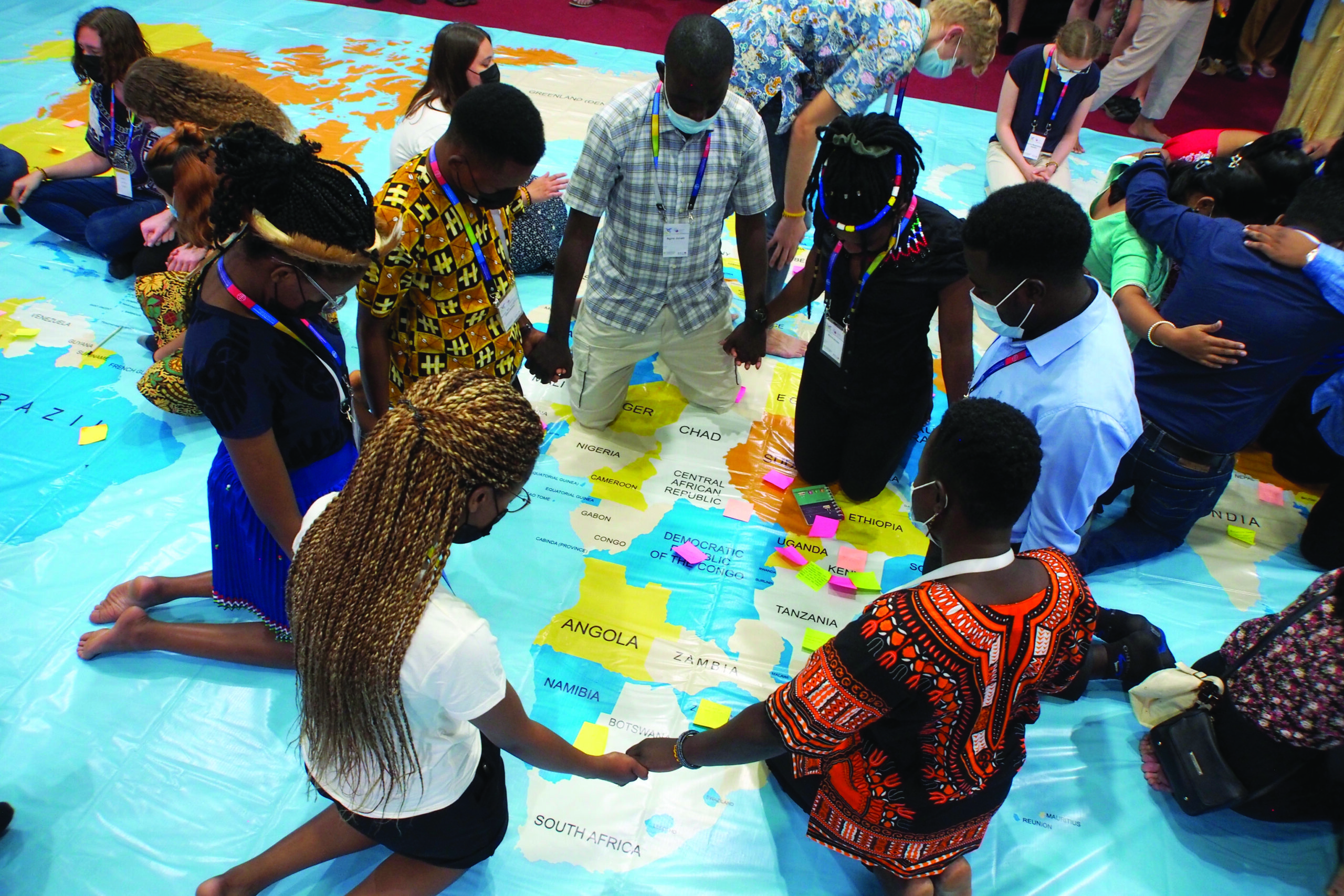 Global Youth Summit participants pray on a world map at the 2022 Mennonite World Conference assembly in Indonesia. - MWC