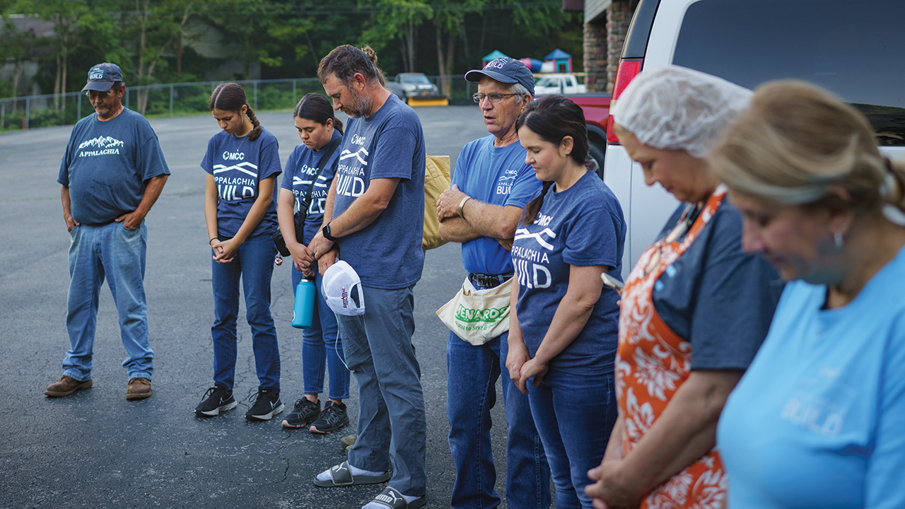 Volunteers and staff of Appalachia Build, a Mennonite Central Committee program, gather at Elkhorn Community Church, Elkhorn City, Ky., for prayer before work on June 7, 2024. —Christy Kauffman/MCC