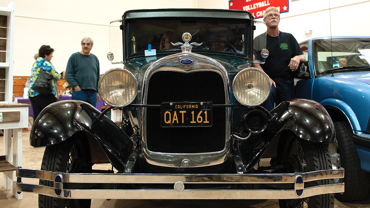 Jerry Koop, right, stands by an antique Ford at the 2013 West Coast Mennonite Relief Sale at Fresno Pacific University in California. — Kevin Malamma