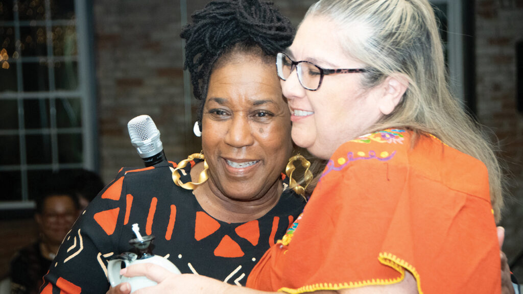 Maati Yvonne, left, one of seven honored community elders, receives congratulations from Ana Alicia Hinojosa. Honorees received oil lamps as tokens of thanks for lighting the way forward. — Juan Moya/AW