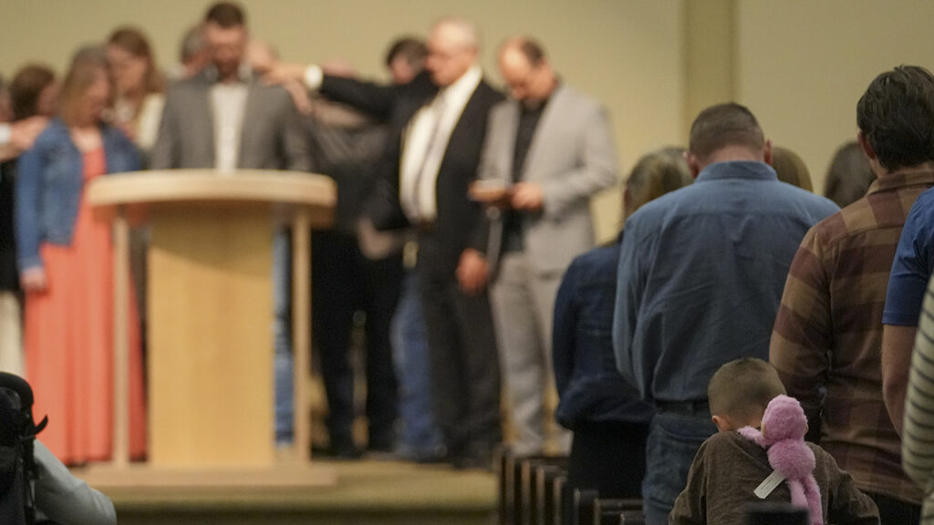 A child hangs a stuffed animal on his back as elders pray for Johnny Dyck as he is ordained as a pastor during a service at Community Church of Seminole, Texas, on Feb. 23. — Julio Cortez/AP