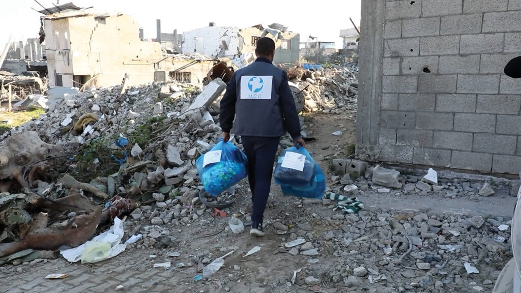 A staff member from Al-Najd Developmental Forum delivers comforters and hygiene supplies to Palestinians who had returned to their bombed houses in northern Gaza. — Mahmoud Meqdad/MCC