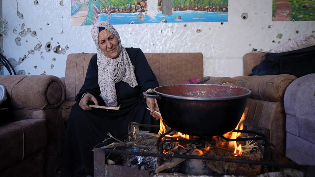 Khayria tends a fire in the one room of her house in northern Gaza that is still standing. She uses the fire for cooking and for keeping her grandchildren warm at night. — Mahmoud Meqdad/MCC