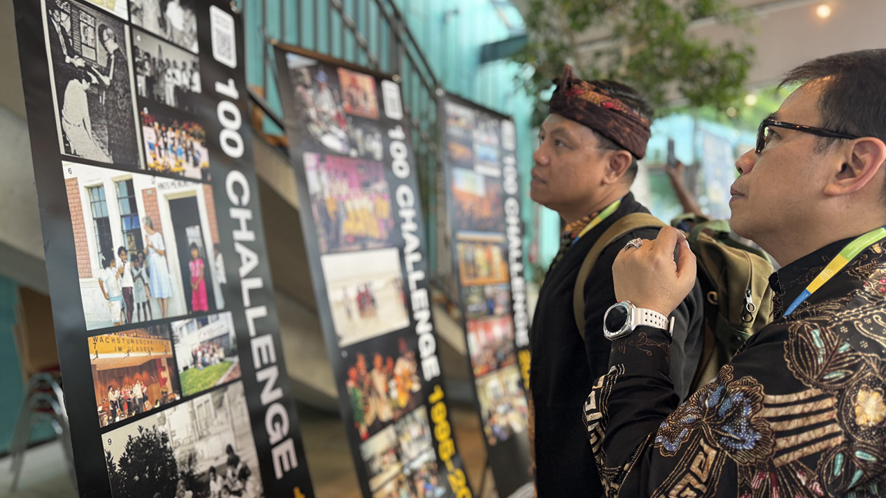 Agus Mayanto, left, and Timotius Adhi Dharma, both from Indonesia, view banners displaying pictures collected from Ana­baptist churches around the world to illustrate Mennonite World Conference’s 100-year history. — Elina Ciptadi/MWC