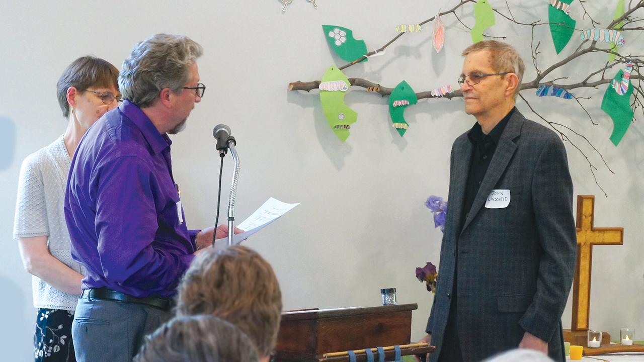 Western District Conference moderator Eric Buller reads an apology to John Linscheid on May 11 at Peace Mennonite Church in Lawrence, Kan., as conference minister Heidi Regier Kreider looks on. — Ken Ratzlaff