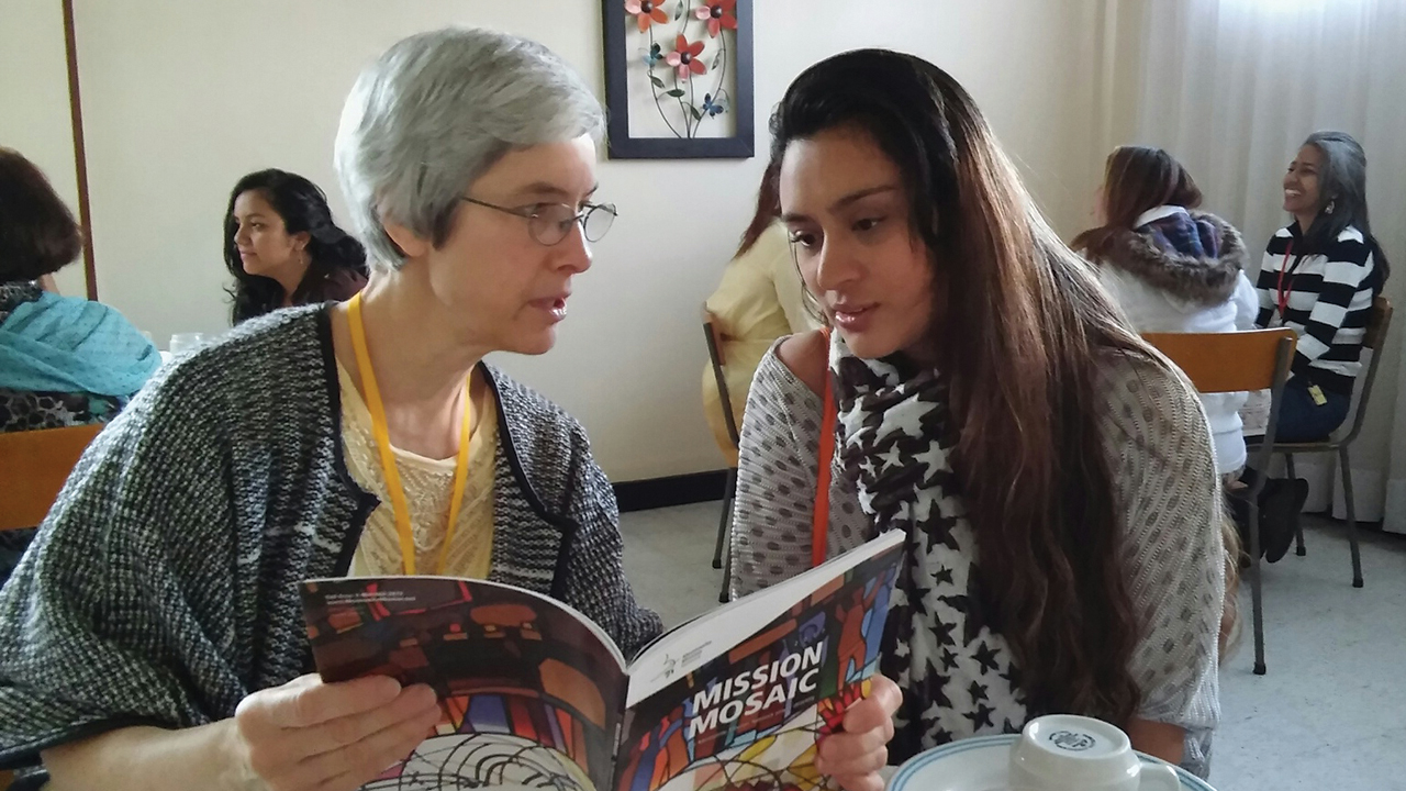 At a Sister Care seminar in 2017, Linda Shelly shares with Cielo Arguello the inclusion of her ministry in Iquitos, Peru, in the Mennonite Mis­sion Network prayer directory. — Rhoda Keener/MMN
