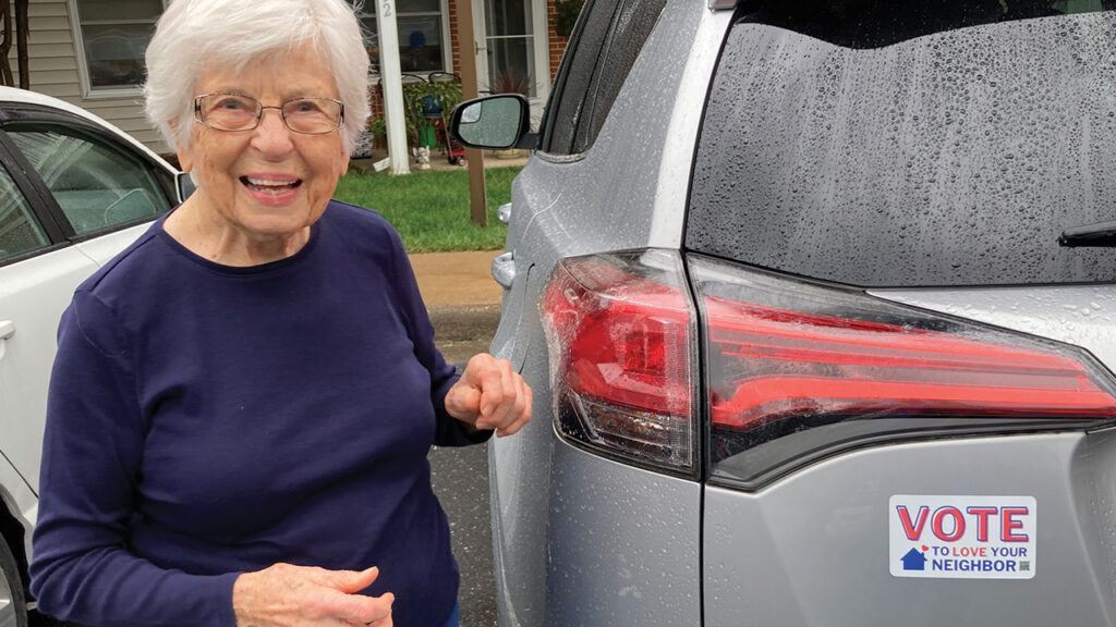 Dorothy Shank with a car magnet bearing a reminder to think about Jesus’ message in Luke 10 about loving God and loving neighbors. — Ridgeway Mennonite Church
