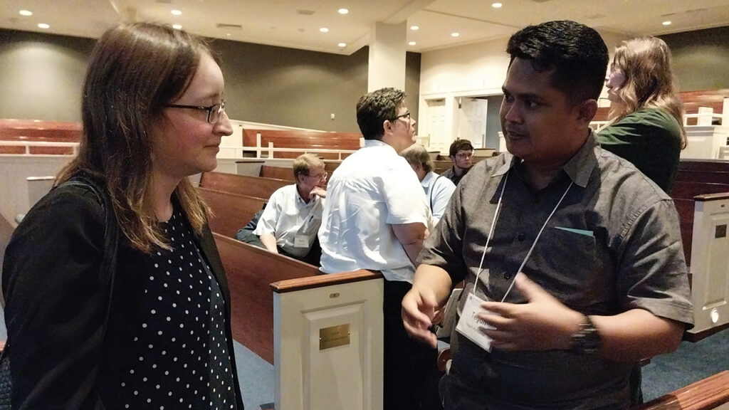 Julia Wiker, left, of Mennonite Life, talks with Teguh Karyanto of Indonesia. Mennonite Life, formerly Lancaster Mennonite Historical Society, cosponsored the conference. — Eileen Kinch/AW