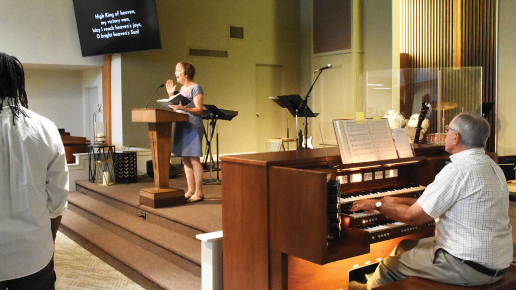 Kathy Heinrichs Wiest leads the opening hymn at Hope Kingsburg’s final service, accompanied by organist Don Adams, who has served as organist for more than 50 years. — Steve Wiest