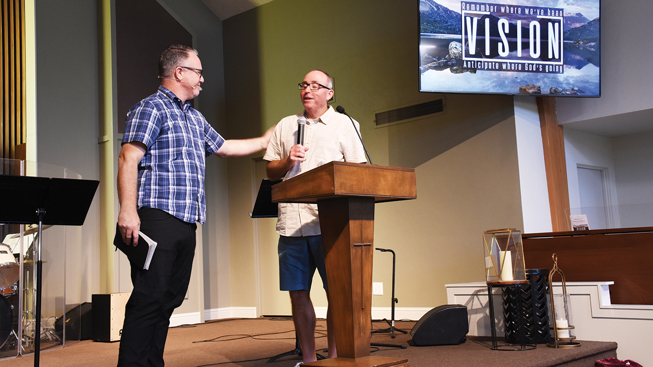 Clayton Paull, left, pastor of Hope Kingsburg, hands the microphone to Forrest Jenan, lead pastor of Neighborhood Church, at Hope Kingsburg’s final service. — Steve Wiest