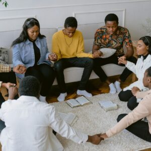 People sitting in a circle, holding hands while praying.