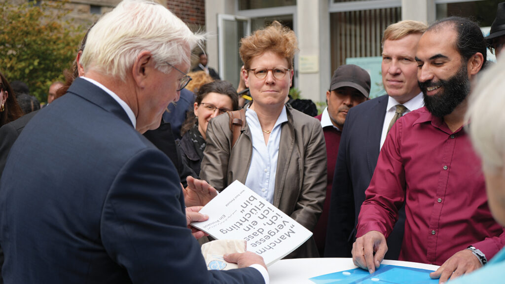 Victor P. Banakar, right, presents Frank-Walter Steinmeier with his refugee story as Mennonite historian Astrid von Schlachta, center, observes. — Brigitte Schulz