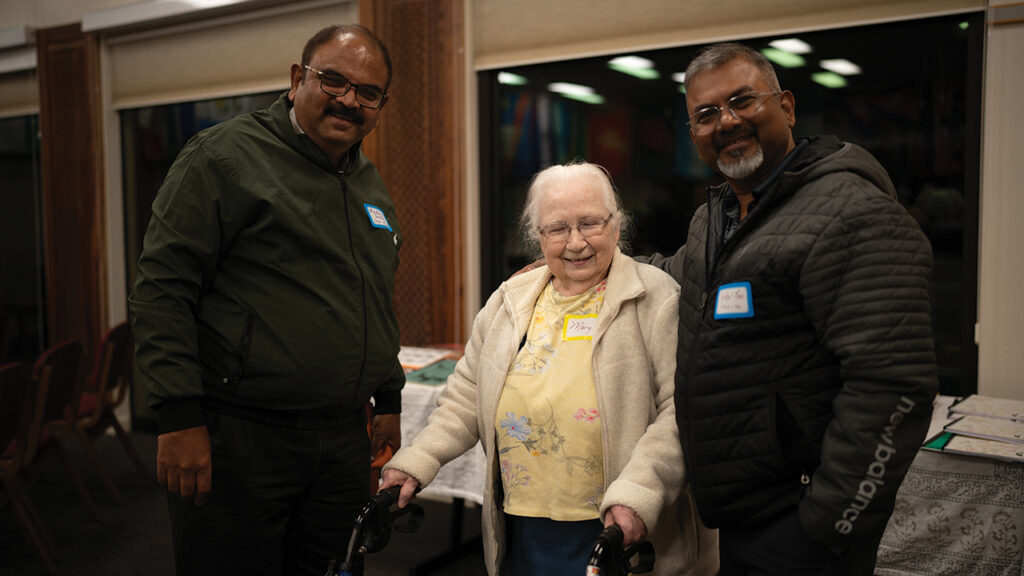At the IVEP anniversary gathering in Akron, Pa., Madhur Kant Gardia, left, and Vikal Pravin Rao, right, who both came from India in 1993-94, greet Mary Martin, a longtime IVEP host in Akron as well as a longtime staff member at the MCC Material Resources Center in Ephrata. — Christy Kauffman/MCC