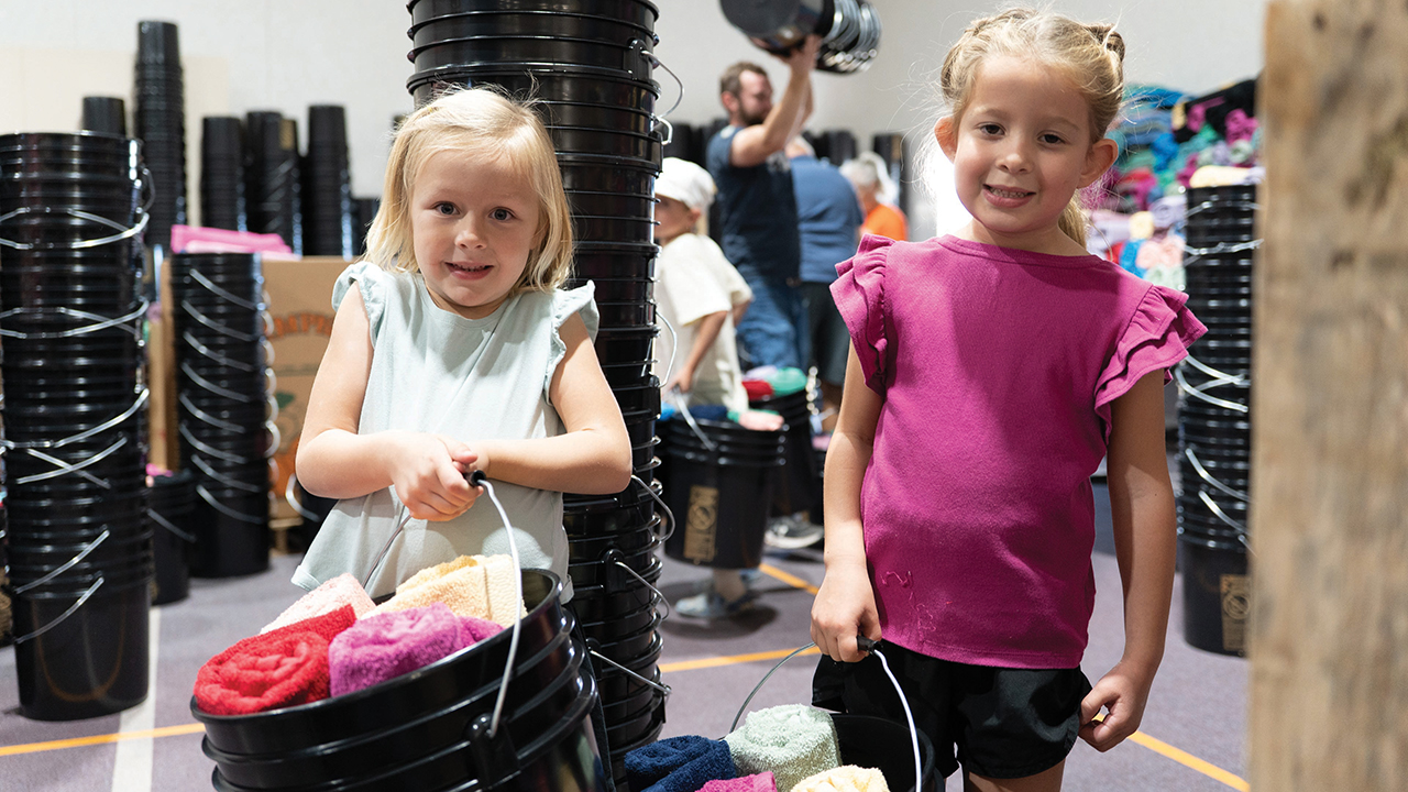 Hazley Cillers and Riley Miller, both 5 years old, carry buckets filled with hygiene items during Pleasant View Mennonite Church’s fourth annual relief kit packing event. — Jake Smucker/MCC