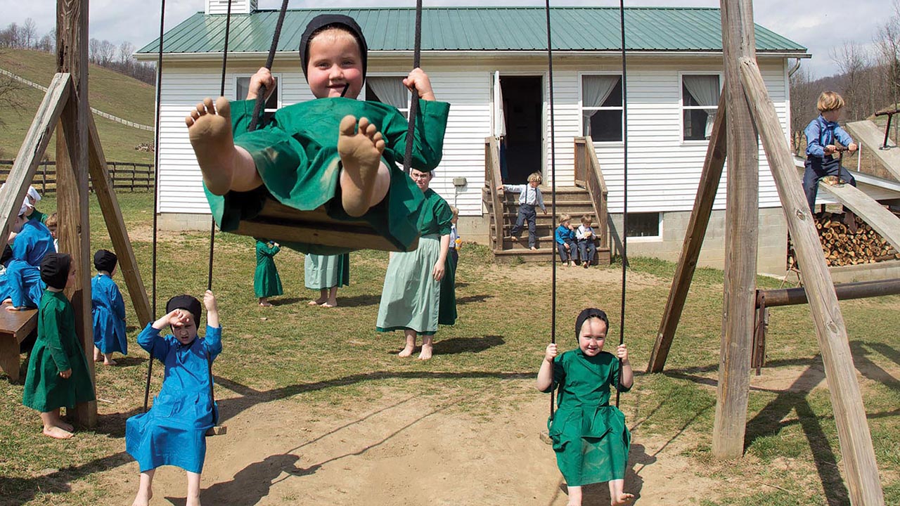An Amish girl swings on a swing set while others play outside the school house in Bergholz, Ohio, on April 9, 2013. Amish families enjoyed a celebration following classes on the last day of school. — Scott R. Galvin/Associated Press