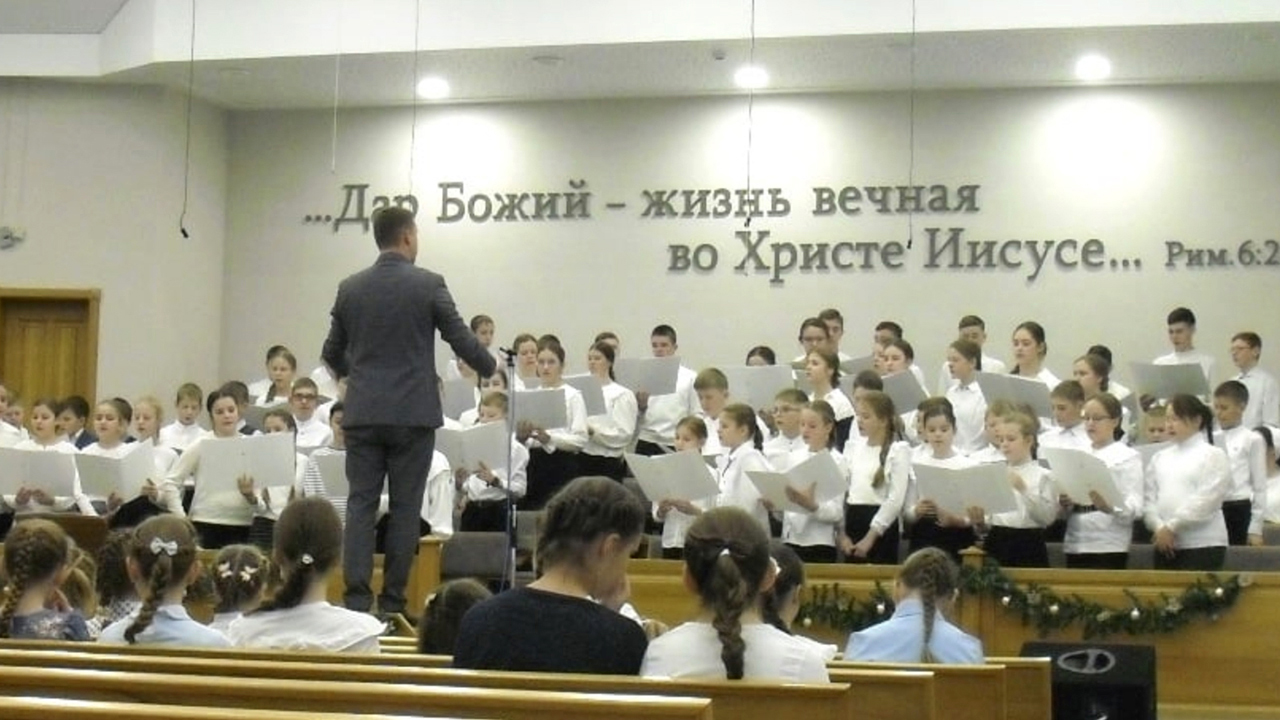 A children’s choir sings during an evening service in December in Apollonovka, Russia. The verse on the wall is from Romans 6:23. — William Yoder