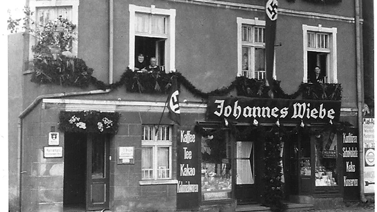 Nazi flags adorn a building in Tiegenhof in 1934 in the Free City of Danzig, Germany. The town was home to many Mennonites, and this building was owned and managed by Ida Epp, sister to Gerhard Epp. Gerhard Epp was a member of a Mennonite church and the NSDAP and ran a factory during the Second World War that used forced labor from the Stutthof concentration camp. — Bruck Family Blog
